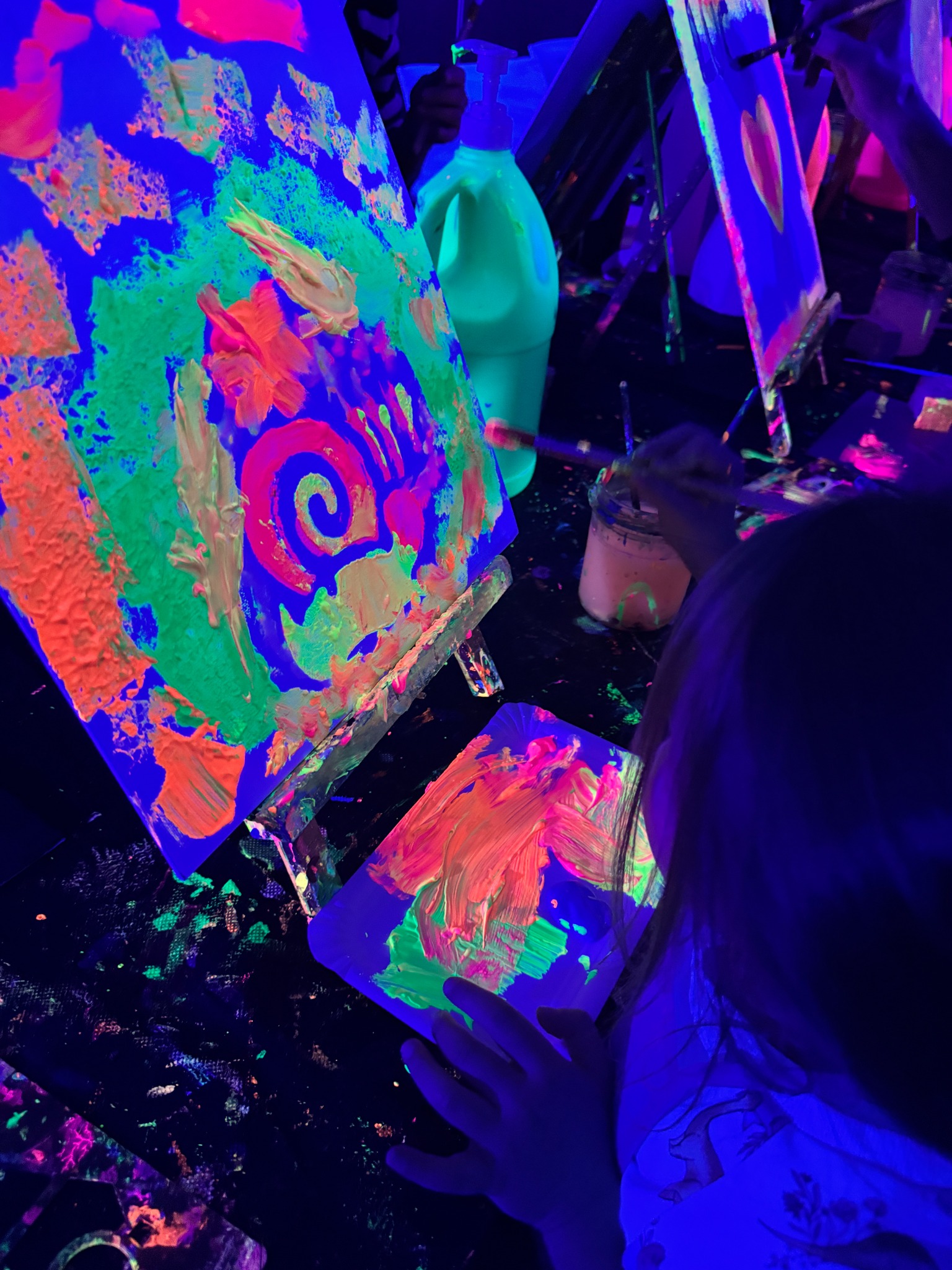 Ein Kind gestaltet eine Neon-Leinwand mit Pinsel und Farbpalette.